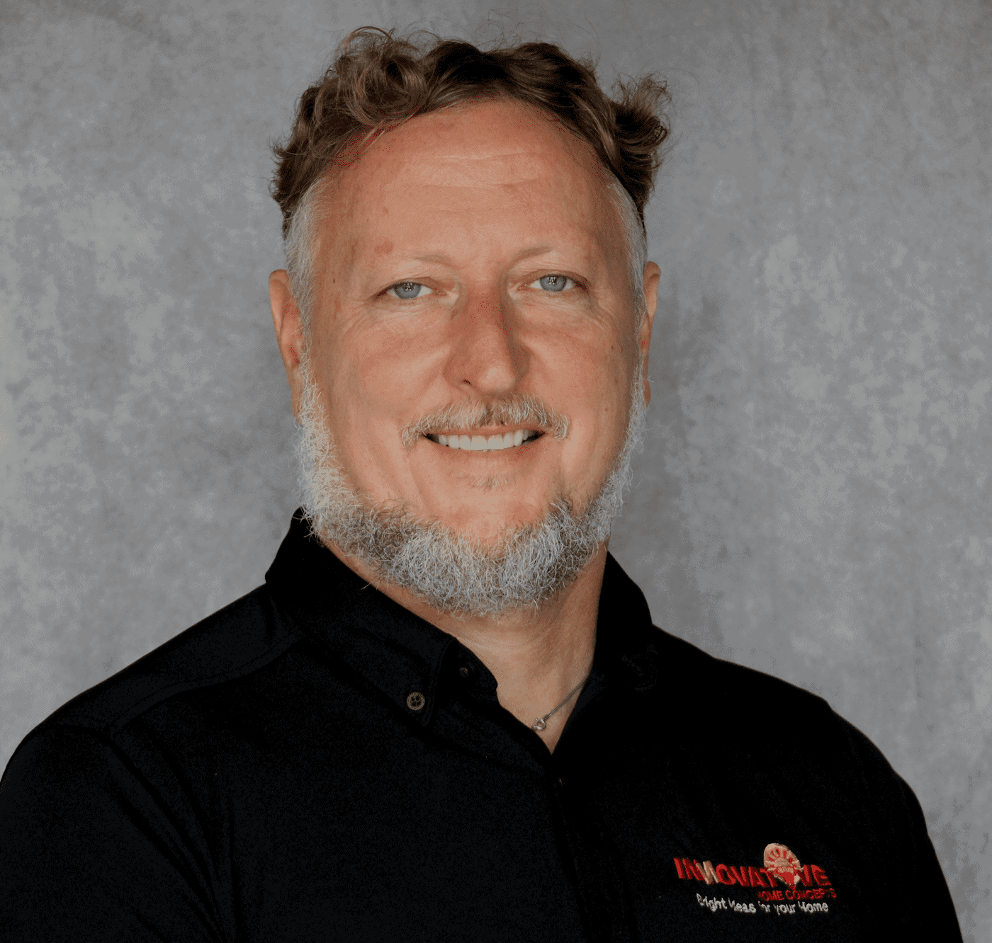 Man smiling in black shirt with Innovative Home Concepts logo.
