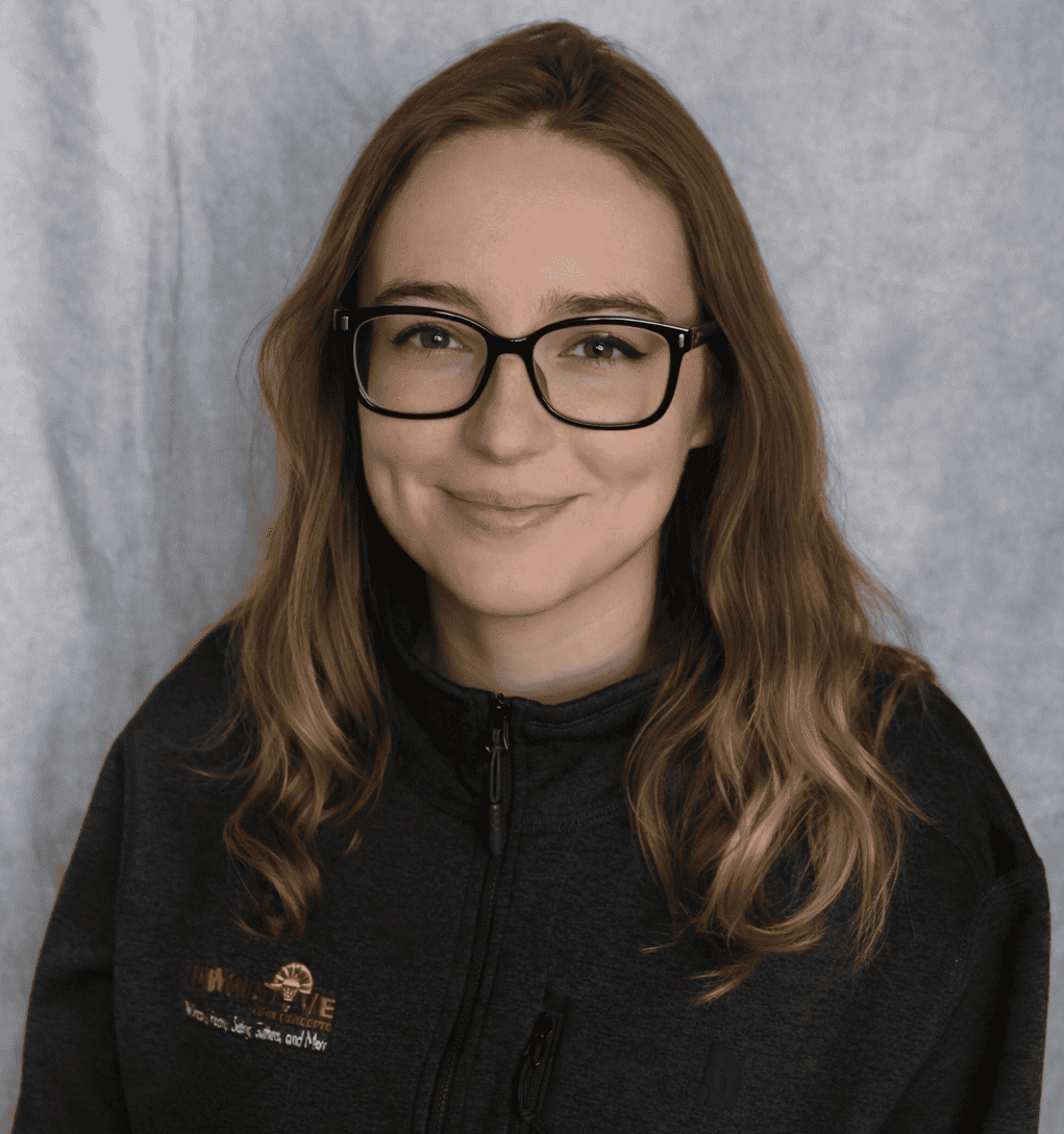 Woman smiling in black jacket with company logo, professional portrait.
