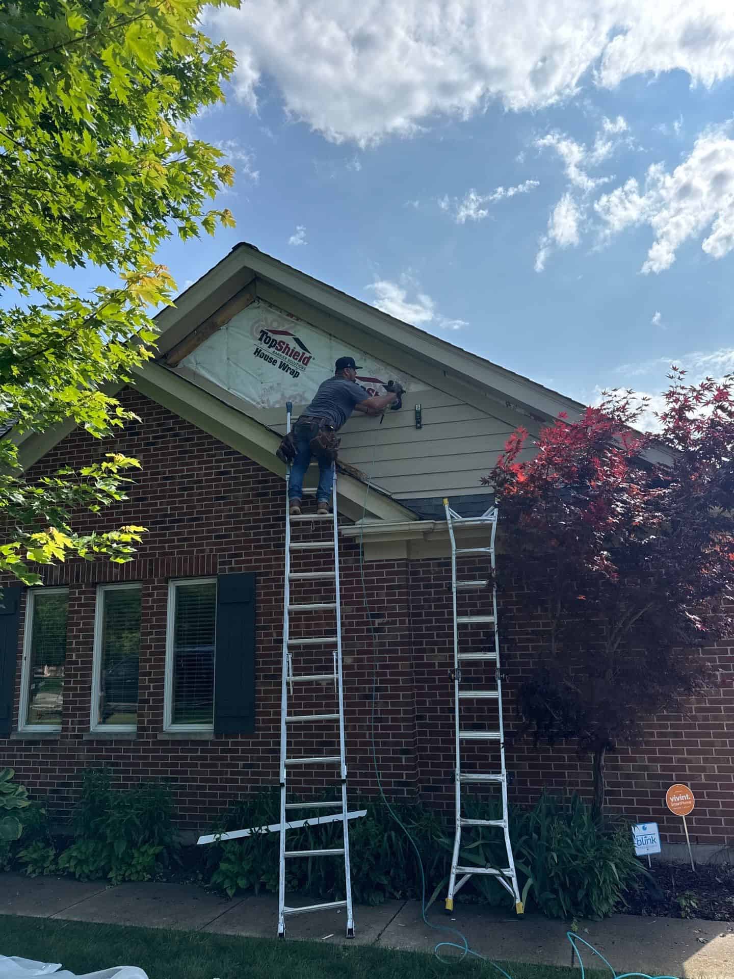 Professional worker installing siding on a residential home