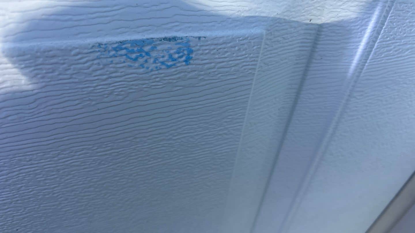 Hail impact bruise on a white panel garage door in Cary, IL &mdash; visible paint chip from the August 2025 hail event