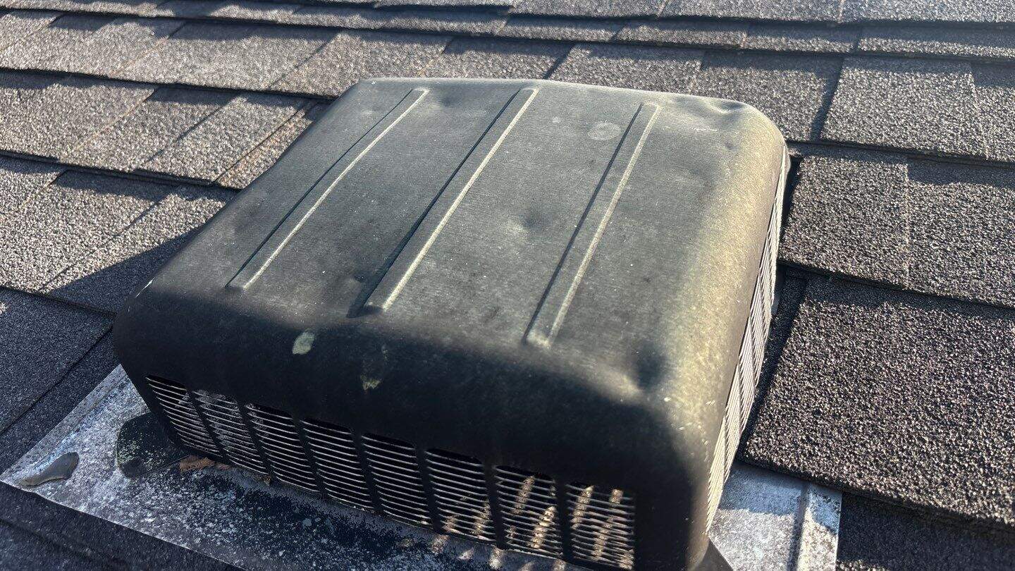 Hail damage to a metal roof vent — dented from hail impact in McHenry County