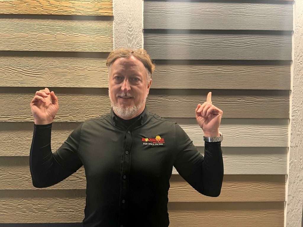 Rhett Wilborn comparing James Hardie and LP SmartSide siding displays at Innovative Home Concepts showroom