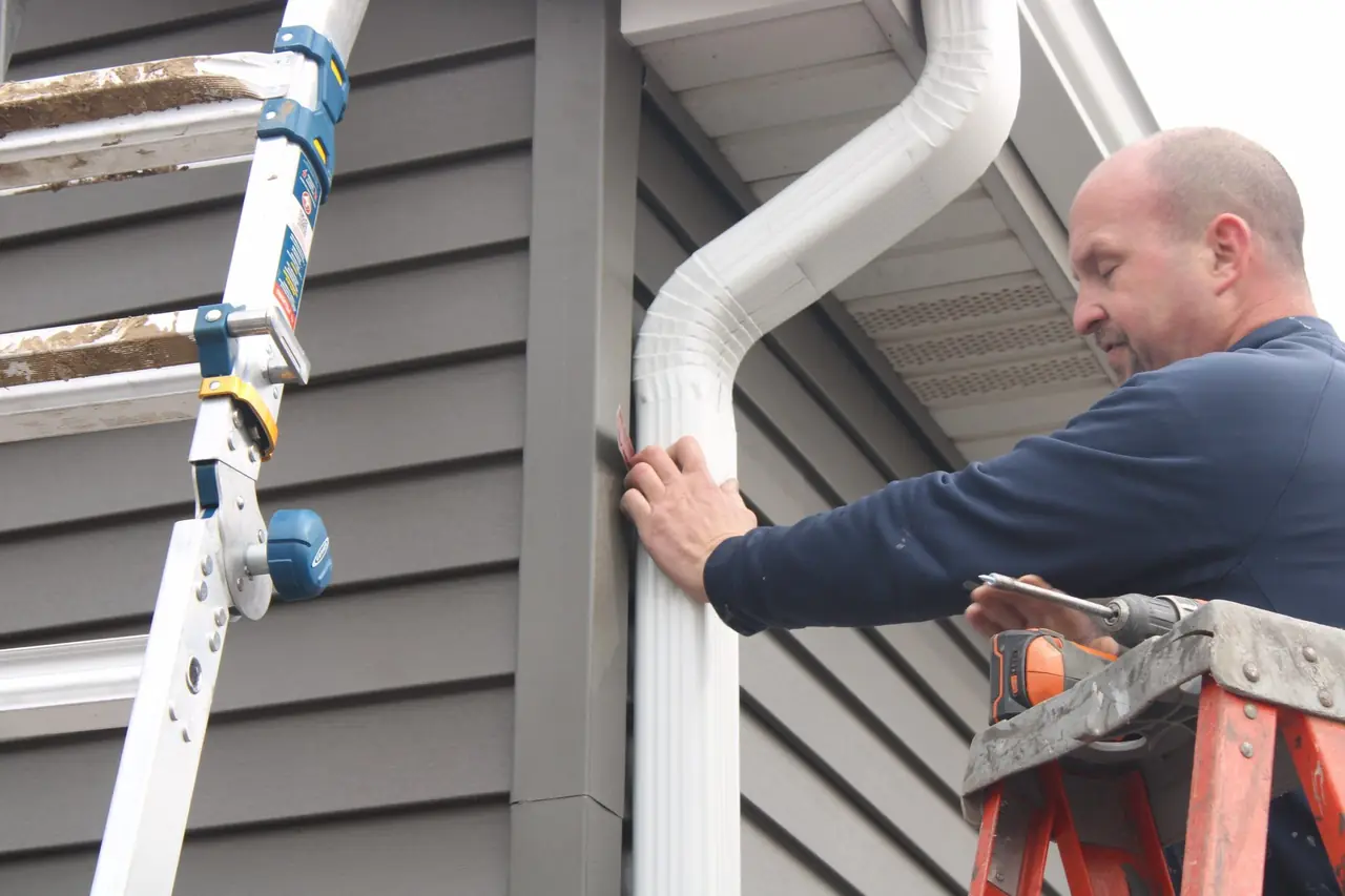 IHC installer Nate installing a new downspout on gray siding