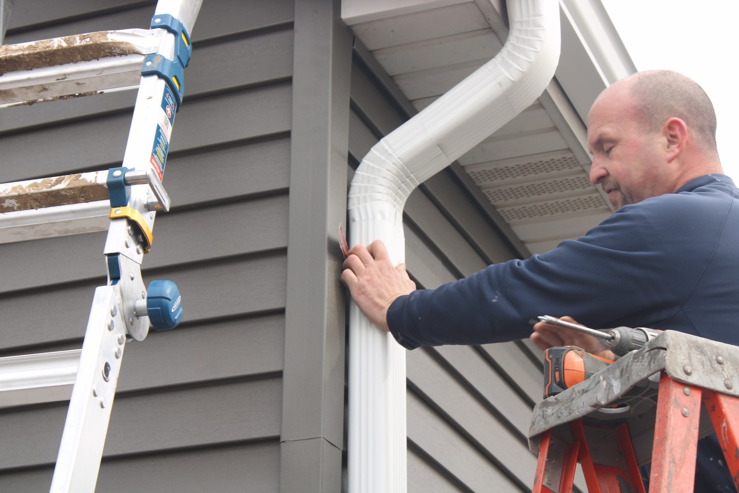 IHC installer Nate installing a new downspout on gray siding