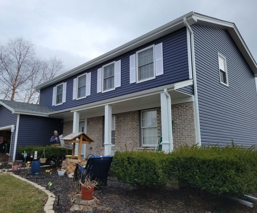 Veretta Court McHenry IL after — navy vinyl siding, white columns, new roof, fascia, soffit, and gutters