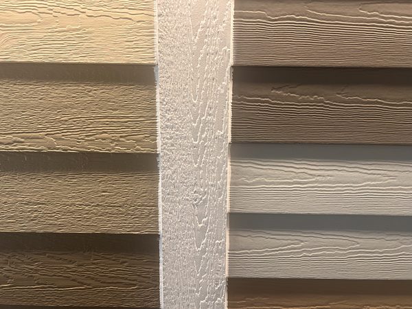 James Hardie fiber cement and LP SmartSide engineered wood samples side by side with PVC trim board between