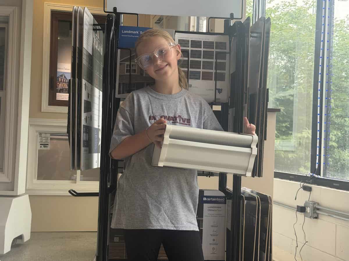 Olive holding a GutterShutter sample at the IHC Crystal Lake showroom