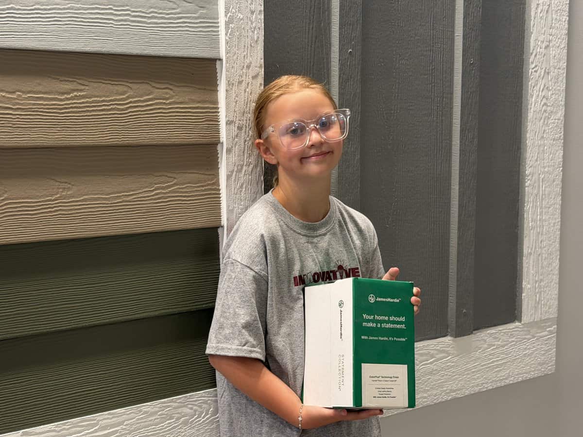 Olive holding a Hardie siding sample at the IHC Crystal Lake showroom